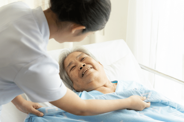 高齢者に布団をかけている女性